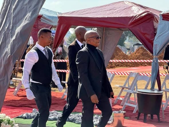 B2K Funeral Services attendants walking beneath a service tent